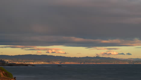 Panning-Timelapse-of-Clouds-Passing-Over-Coastline-with-Lighthouse-and-Rainbow