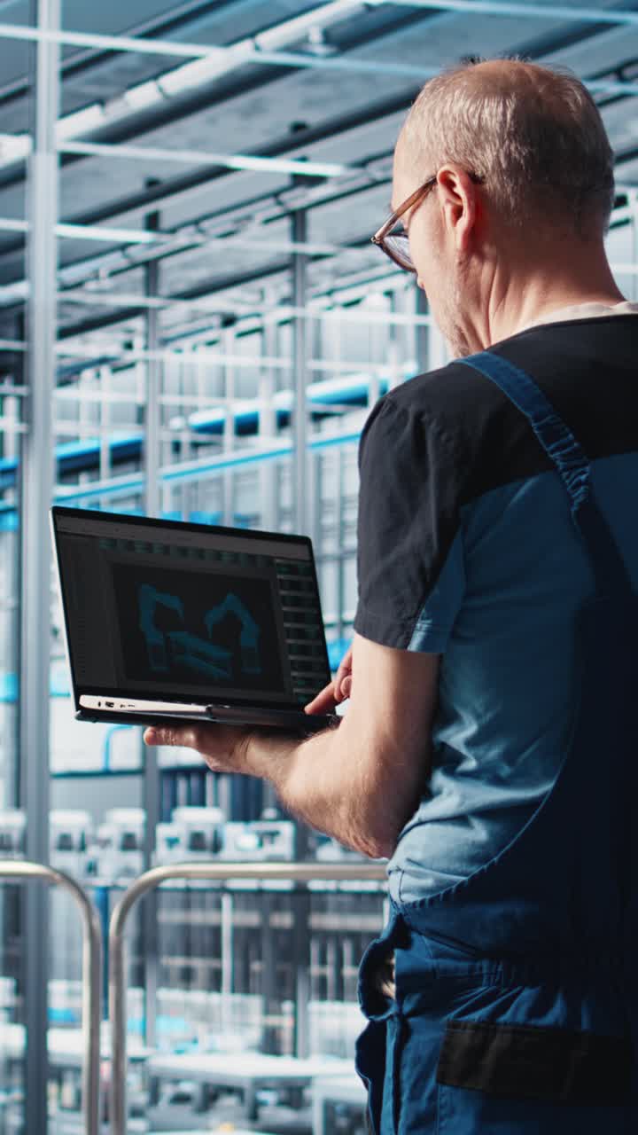 Vertical video Smart factory expert using laptop software to test automated systems