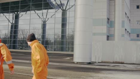 Two-construction-workers-in-orange-uniform-and-helmets-walking-together.-One-of-them-lost-his-helmet.-Having-fun