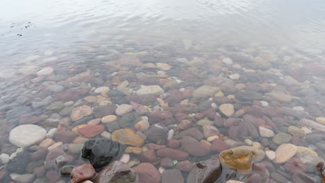 waves moving in and out over colourful natural stones