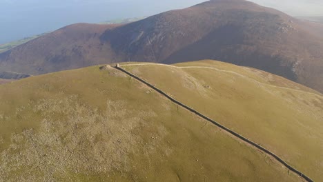 corner on slieve donard mountain peak of mourne wall, establishing shot as drone tilts down