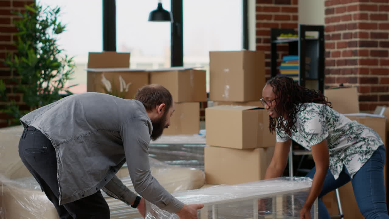 Diverse couple carrying table in living room to move in