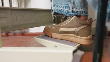 foot pedal stepped on by tailor controlling stitching pace, ensuring accuracy and skillful operation, promoting stable posture, focusing on smooth movement, enabling precise garment production