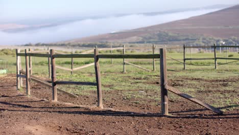 Wooden-fence-on-agricultural-field-at-countryside-on-sunny-day,-slow-motion