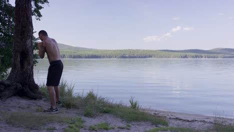 man training boxing outdoors by lake