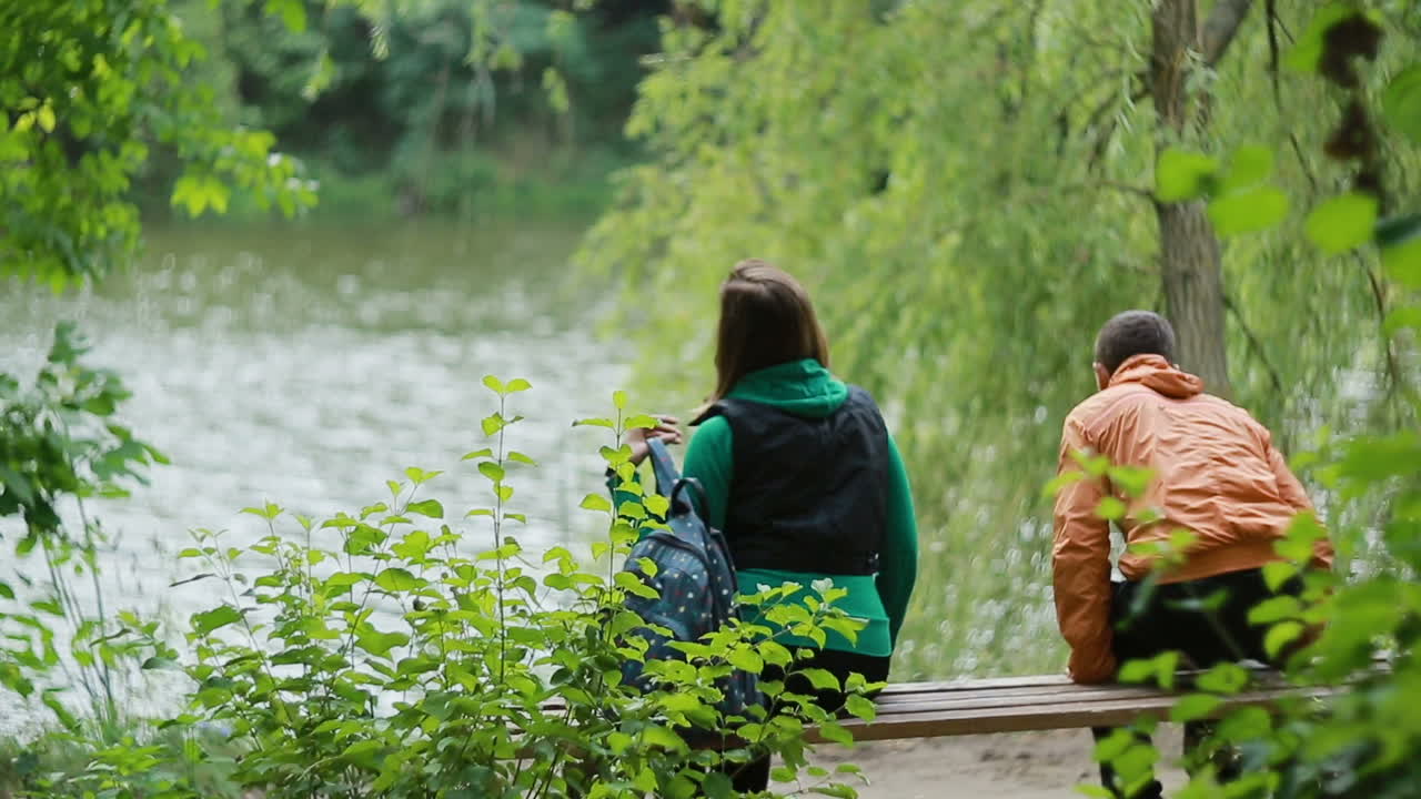 Couple On Bench In Nature. Happy young couple in love sitting on a park bench