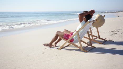 un joven biracial se relaja en una silla de playa junto al mar con espacio de copia