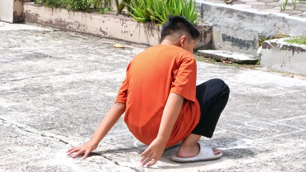 พี่ชายกำลังตั้งสมาธิและวางตำแหน่งบนตารางเล่นตั้งเต โดยมีน้องเฝ้าดูอยู่เบื้องหลัง