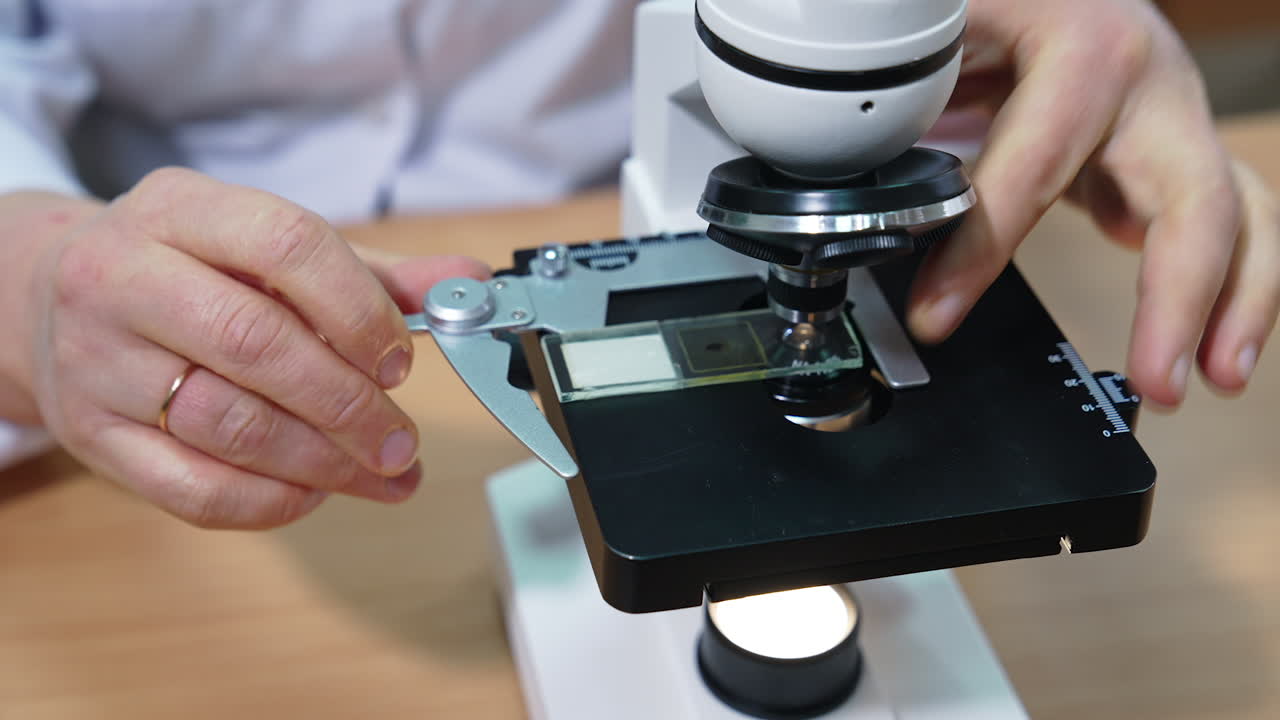 Laboratory researcher puts the sample under the microscope. Medical laboratory at modern hospital. Close up.