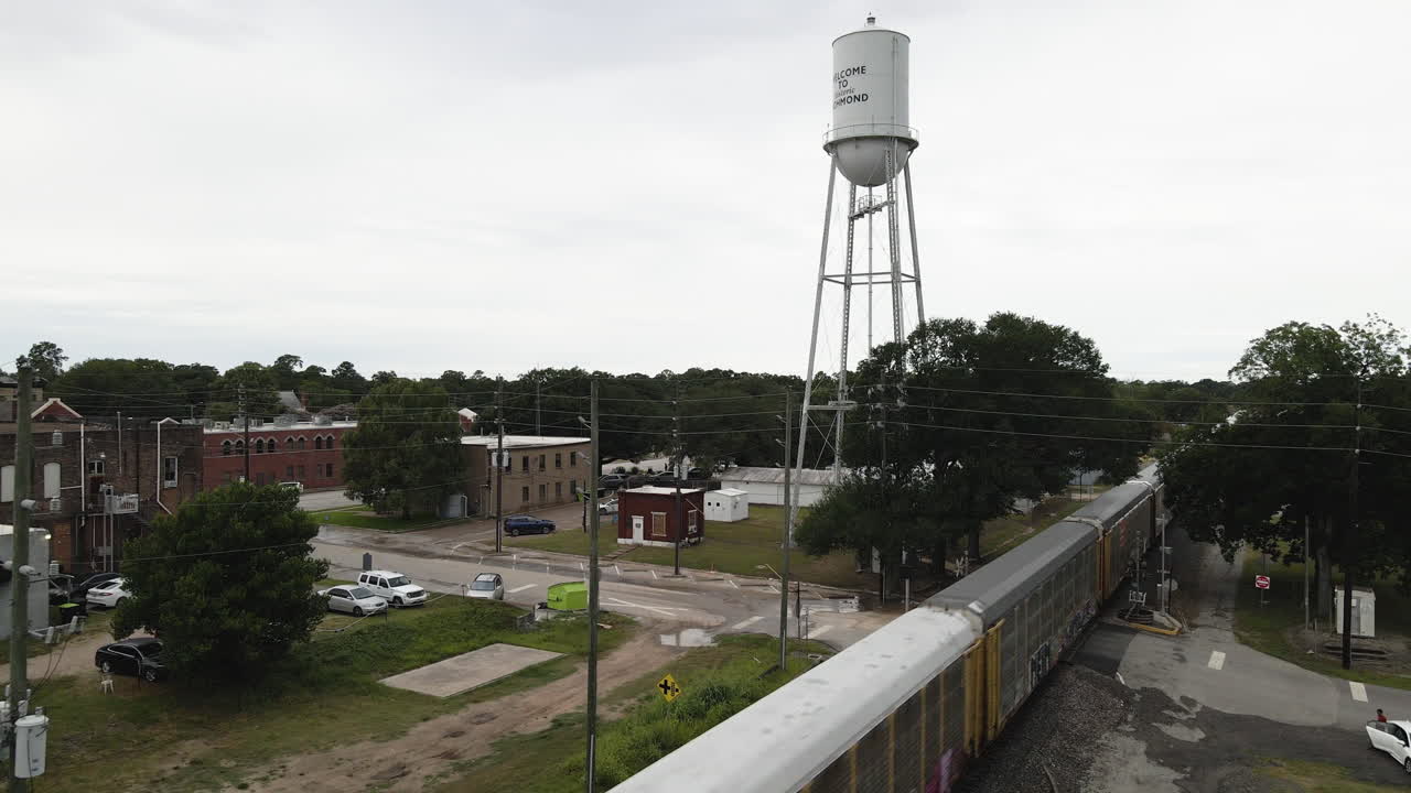el tren de carga pasa la torre de agua en una pequeña ciudad de texas