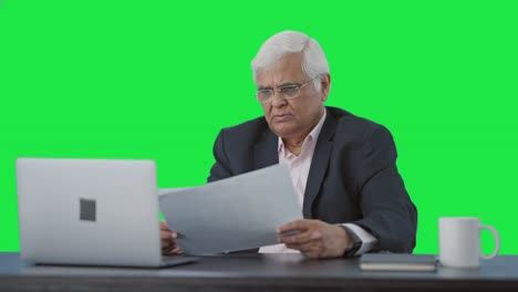 serious indian senior manager reading business reports green screen