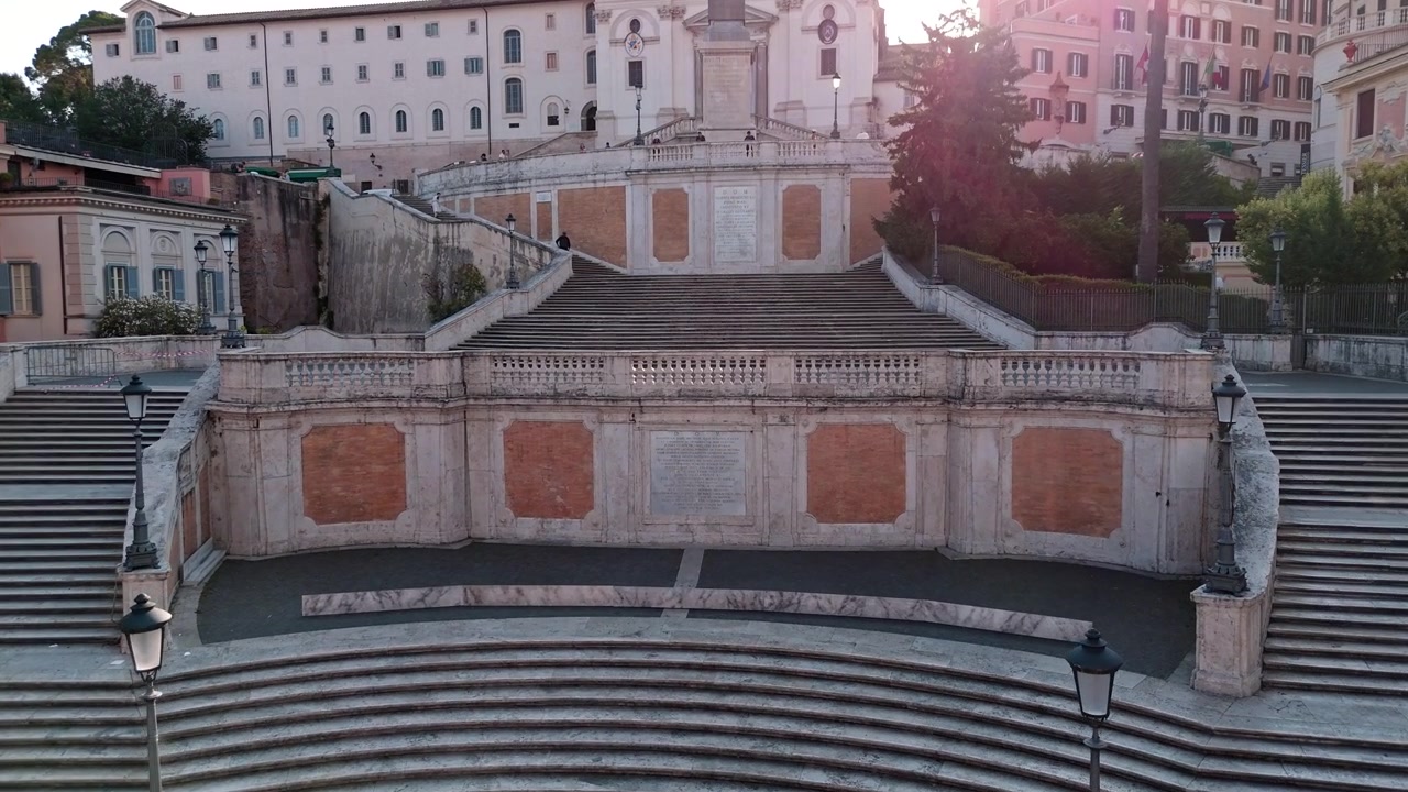Piazza di Spagna e la Scalinata di Trinità dei Monti sono quasi vuote mentre un drone sale nella morbida luce dell'alba.