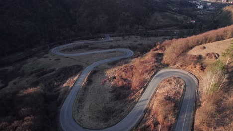 aerial view of a car driving along scenic curvy serpentine road in the mountains with ascending and tilt movement