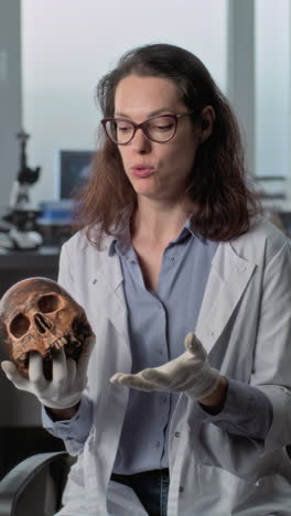 scientist presenting a human skull in a laboratory setting