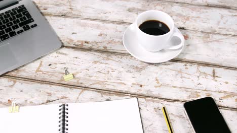 una taza de té, portátil, teléfono inteligente, diario y lápiz
