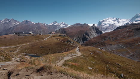 Hiker-in-the-Alps-Mountains-by-a-Lake-with-Cable-Cars-in-the-Background