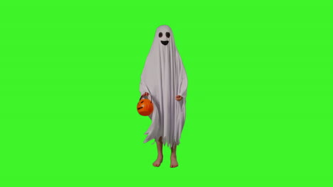 toma completa de un niño vestido con un disfraz de fantasma llamando a la puerta truco o trato en halloween sosteniendo un cubo en forma de calabaza jack o'lantern contra la pantalla verde del estudio