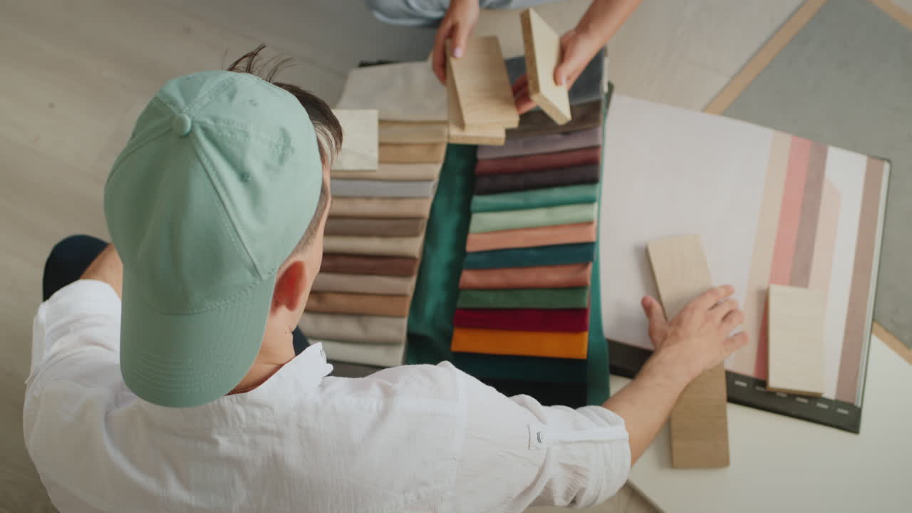 dos diseñadores seleccionan el color y la sombra de la madera y la tela, frente a ellos álbumes con muestras. creativo kamanda