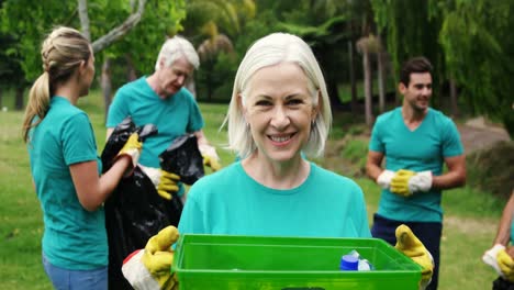 mujer mayor sosteniendo un contenedor de reciclaje