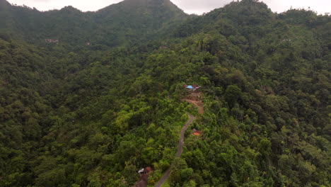 aerial view of lush green mountains with remote houses and winding road
