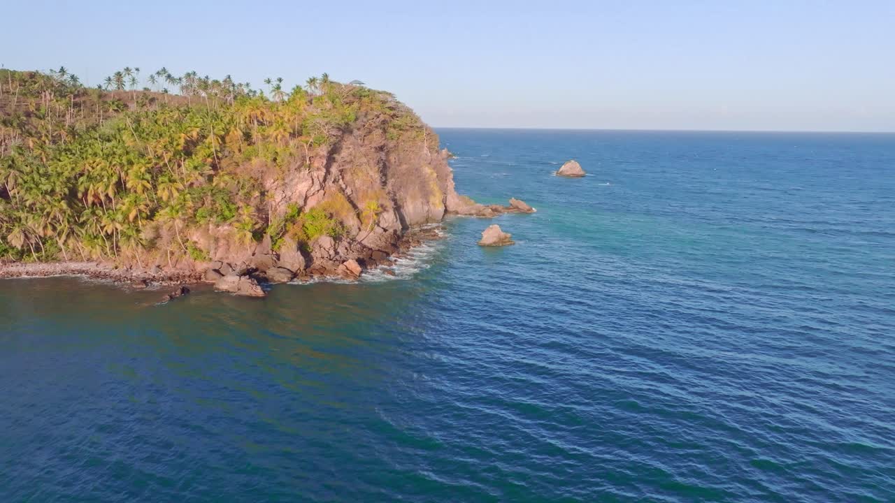 drone estableciendo una toma de una isla tropical con palmeras y el tranquilo mar caribeño a la hora del atardecer dorado