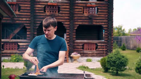 young man makes pilaf in a cauldron on a grill on an open fire stir the meat and carrots