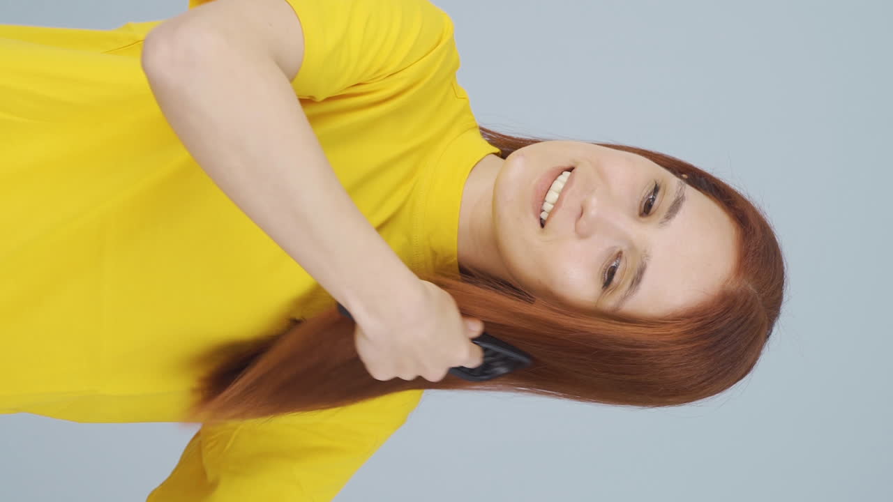 머리카락을  ⁇ 는 여성의 수직 비디오. 머리카락 관리.