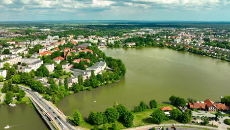 Aerial-view-of-Iława,-a-scenic-town-with-a-large-lake-surrounded-by-lush-greenery-and-residential-buildings