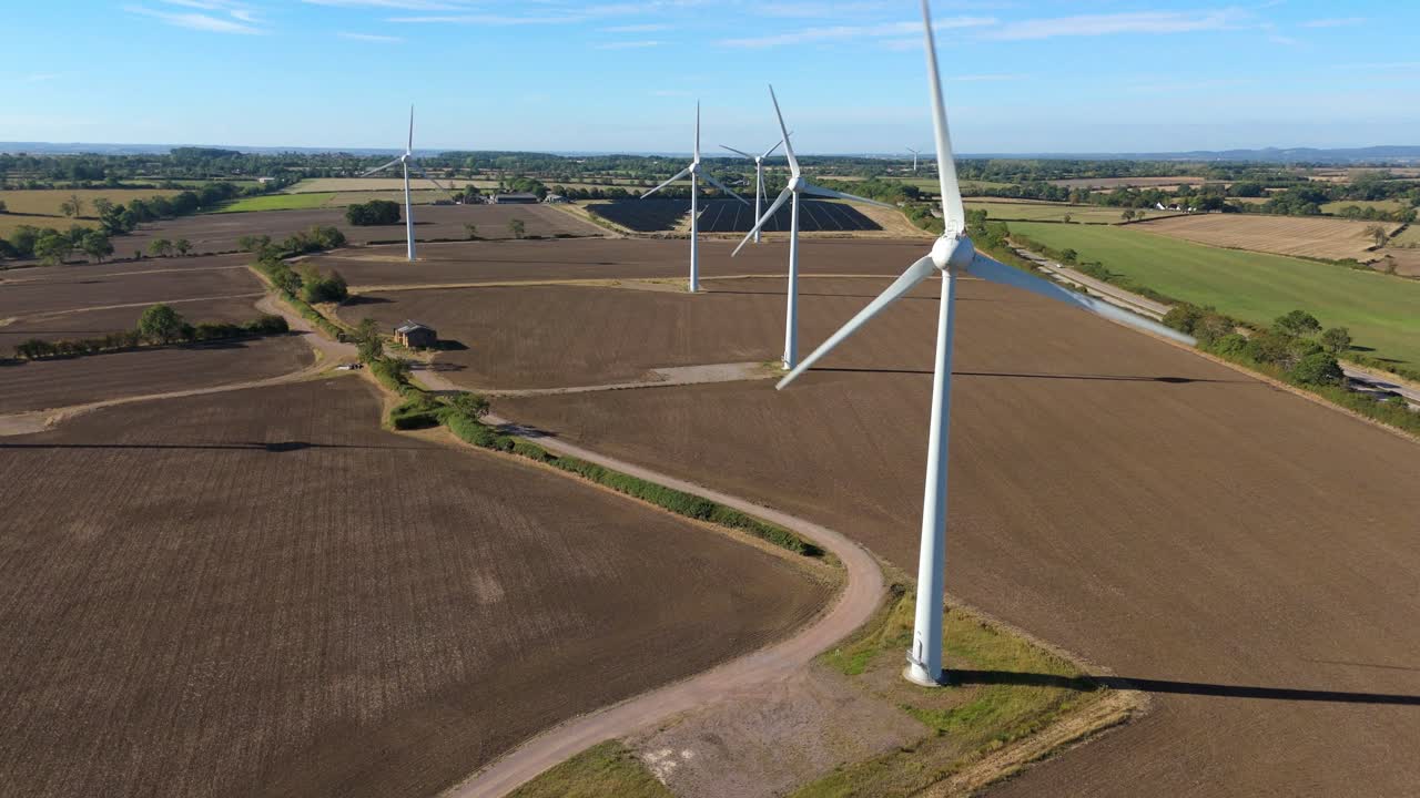 Drone flight through renewable energy landscape with turbines and solar panels, rural England, United Kingdom