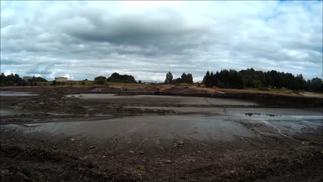 the bulldozer pushes the mud sludge on the bottom of the drained river