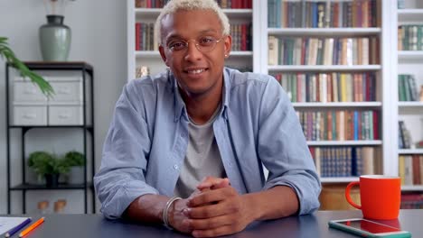 young african american man looking at camera with smile sits in own office