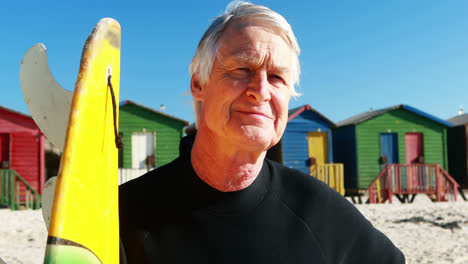 senior man with surfboard standing on beach