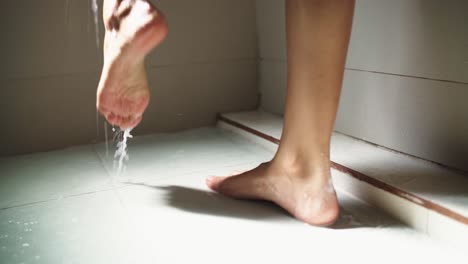 young woman steps from one foot to another while taking a shower in the morning