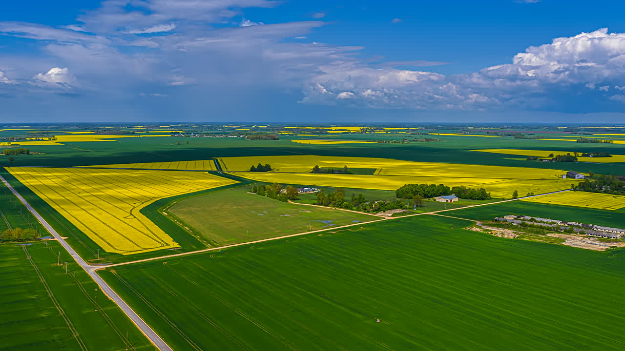 Magical aerial cloudscape time lapse from high altitude as clouds and shadows pass over farmland fields in rural Latvia with rapeseed and gain crops to the horizon