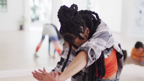 Biracial-female-dancer-stretching-with-diverse-colleagues-in-dance-studio,-slow-motion