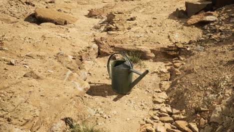 watering can placed on dry ground in an arid landscape for irrigation