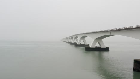 aerial view of a long bridge crossing between islands during thick fog in the netherlands