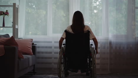 lonely disabled woman moves wheelchair to look out window