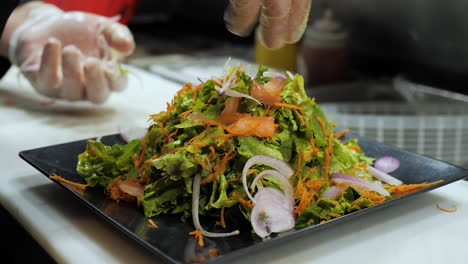 chef sprinkles sliced red onion garnish on tall salad, slow motion orbit hd