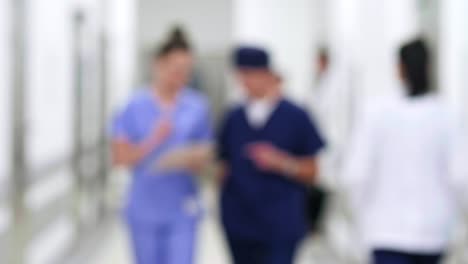 Blurred-motion-of-doctors-walking-through-corridor-in-hospital