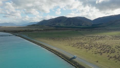 Scenic-aerial-view-of-campervan-traveling-through-fictional-Pelennor-Fields-from-Lord-of-the-Rings-in-Mackenzie-District,-South-Island-of-New-Zealand-Aotearoa