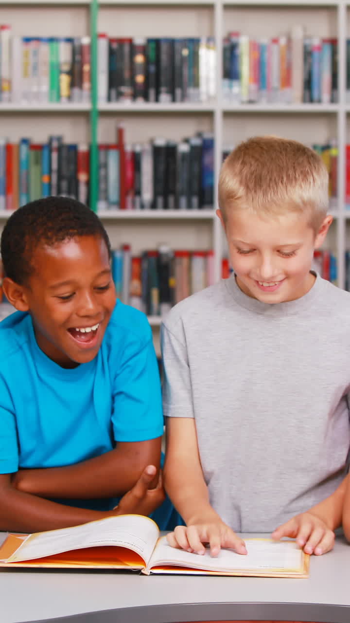 School kids reading book together in library