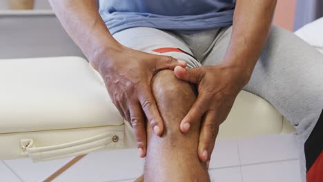 midsection of african american man touching his leg at hospital