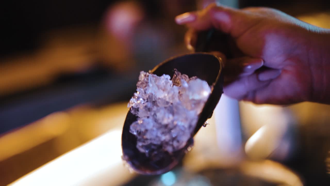 bartender's hand adding ice cubes to shaker in slow motion