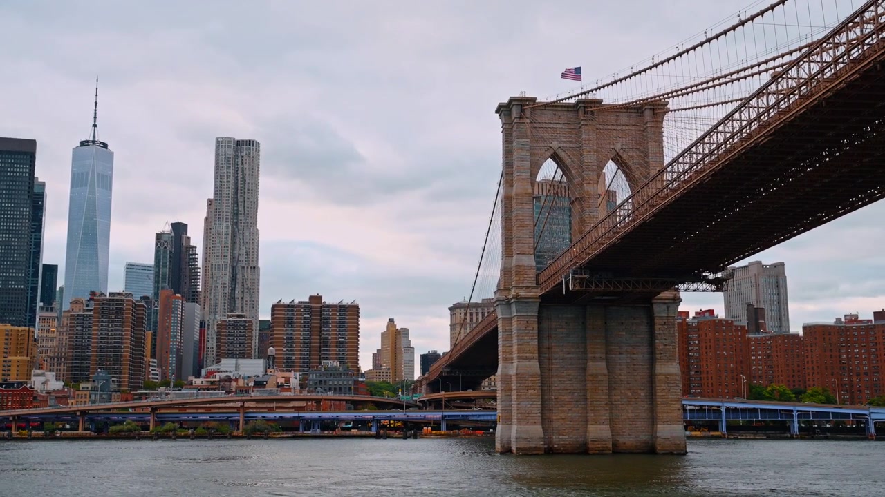 New York, USA, 25 maggio 2026: Torre in pietra del Ponte di Brooklyn con i grattacieli di Manhattan a New York. Architettura del ponte sospeso sull'East River con edifici alti sotto un cielo coperto.