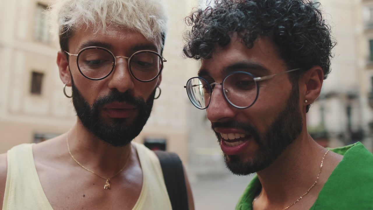 Two Happy Men with Glasses Talking and Smiling on a City Street