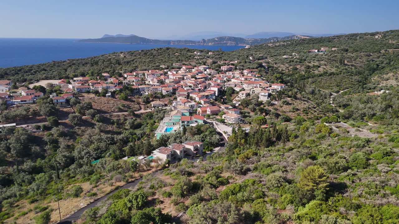 Flyover hilly terrain to Katomeri, Greek village with Ionian sea beyond