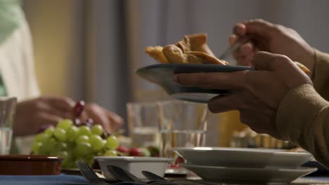 person serving samosas at muslim family table at home set for iftar meal breaking daily fast during ramadan