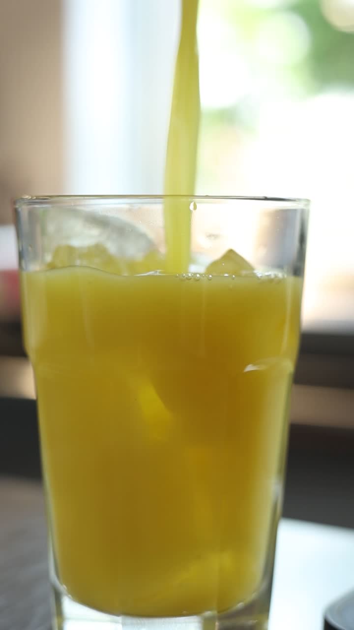 el jugo de naranja se vierte en un vaso con hielo