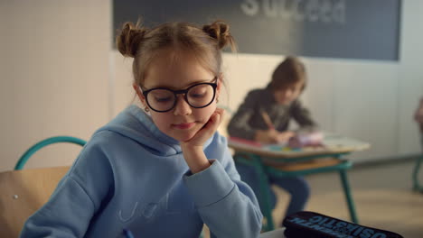 Student-doing-class-work-in-auditorium.-Focused-girl-writing-in-exercise-book